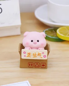 Close-up of pink pig desk ornament holding a calm banner in a cardboard-style base