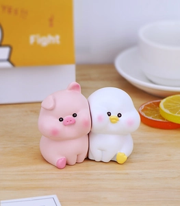 Close-up of cute pink pig and white duck resin ornaments on a bright wooden desk