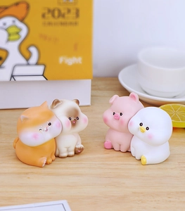 Set of four cute resin animal figurines including a cat, bear, pig, and duck on a wood desk
