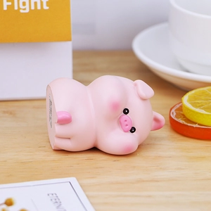 Cute pink pig figurine in a lying pose on a wooden desk for home or office decor