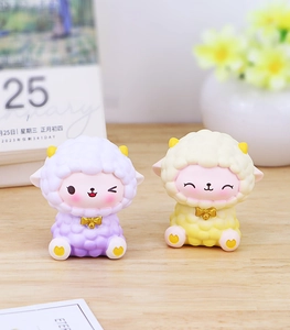 Close-up of cute sheep figurines with golden bows and matte resin finish on desk