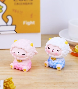 Close-up of cute pink and blue sheep resin figurines with gold horns for home decor