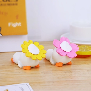 Détail de deux canards mignons en résine avec chapeaux de fleurs sur un bureau en bois