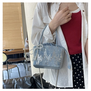 Detail of light blue denim bucket bag with wavy silver sequins and pearl bow charm