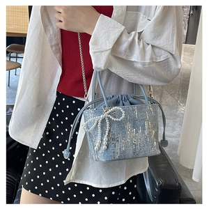 Detailed view of light blue sequin bucket bag featuring a white pearl bow charm
