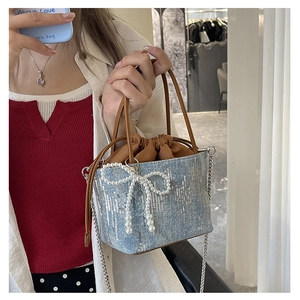 Detailed close-up of a blue sequined bucket bag with large pearl bow and chain strap