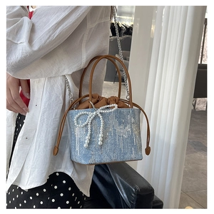 Close-up of blue sequin bucket bag featuring a pearl bow and leather drawstring details