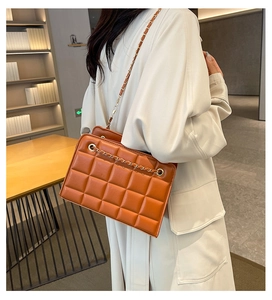 Brown quilted crossbody bag with gold chain strap worn by a model in a modern interior
