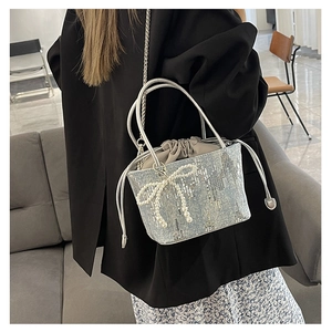 Detailed view of silver-blue sequin bucket bag with pearl bow and silver chain strap