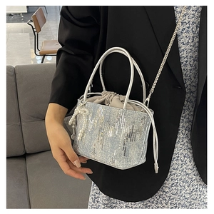 Detail of silver sequin bucket bag featuring a pearl charm and drawstring satin liner