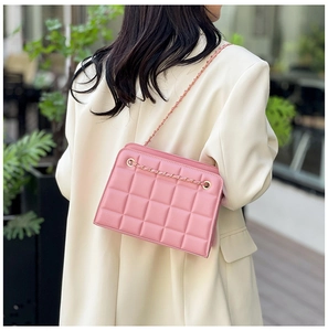 Close-up of pink quilted crossbody bag featuring gold chain and leather strap details