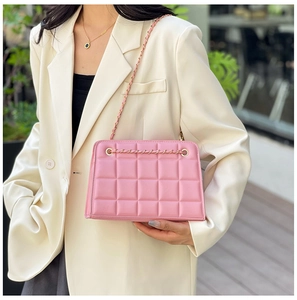 Detail of pink quilted rectangular flap bag with gold chain and leather woven strap