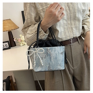 Detail of light blue denim bucket bag with silver sequins and pearl bow charm