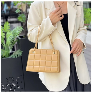 Detail of light brown quilted chain bag featuring classic square grid and gold hardware