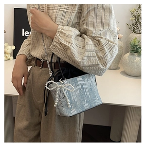 Detail of light blue denim bucket bag with silver sequins and pearl bow charm