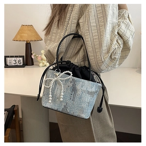 Detail of light blue sequin bucket bag with pearl bow charm and drawstring closure