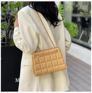 Detail of khaki quilted leather crossbody bag with elegant gold chain shoulder strap
