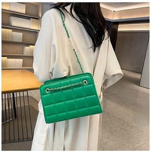 Detail of bright green quilted leather shoulder bag with gold chain and textures