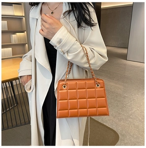 Detailed close-up of caramel quilted crossbody bag with golden chain and retro square texture