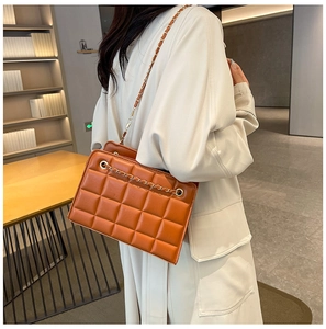 Detail of brown quilted leather bag with elegant golden chain strap and textured finish