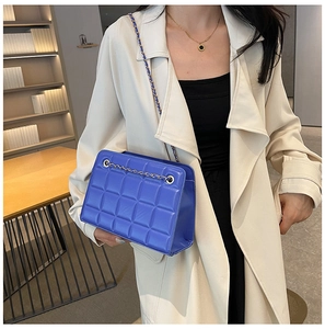 Royal blue quilted chain bag with square pattern shown as a side view on a model