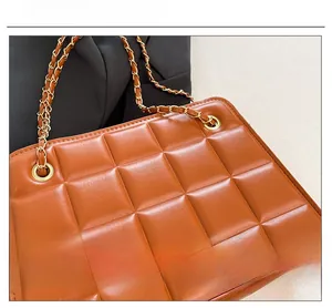 Close-up of brown quilted leather texture with gold chain strap on a small crossbody bag