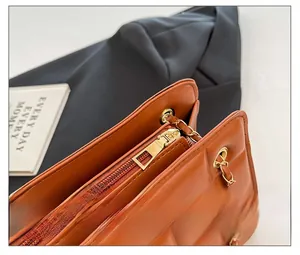 Detailed close-up of smooth gold-tone zipper and quilted faux leather on orange chain bag
