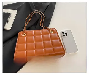 Detailed macro of brown quilted leather texture and gold chain strap on shoulder bag