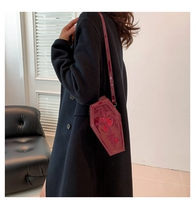 Model wearing a wine red coffin-shaped crossbody bag with floral embroidery detail