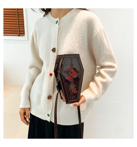 Detailed embroidery of a cross and red rose on a dark brown coffin-shaped PU leather bag