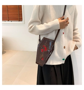 Detail of gothic coffin cross bag with red rose embroidery on dark brown patent leather