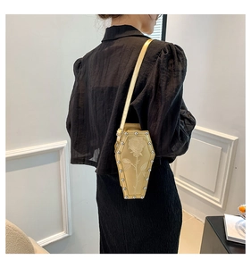 Detail of gold coffin crossbody bag featuring rose texture and silver stud edges