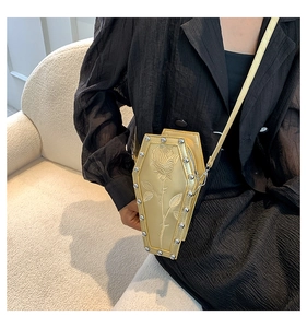 Detail of gold coffin bag with rose embroidery and silver studs on a black dress