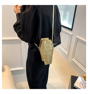 Rear view of gold coffin bag with rose embroidery and silver studs on a black dress