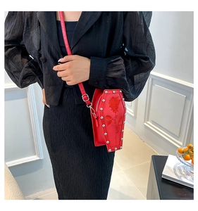 Model wearing a red coffin-shaped crossbody bag with rose relief and silver rivets