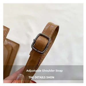 Close-up of adjustable shoulder strap with silver buckle on brown PU leather bag