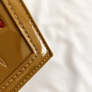Detail of tan glossy patent leather with durable double-row stitching on coffin bag