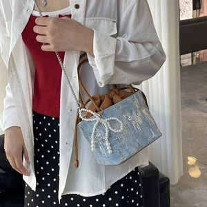 Blue canvas bucket bag with shimmering sequins, pearl bow, and silver chain strap