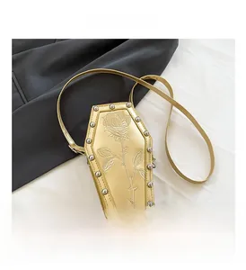 Detail of golden coffin-shaped crossbody bag featuring rose embossing and metal rivets
