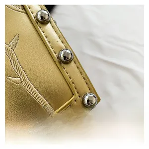 Macro detail of golden faux leather coffin bag with rose embroidery and silver studs