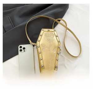 Close-up of golden coffin-shaped crossbody bag with rose texture and silver studs