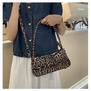 Detail of leopard print shoulder bag with metallic hook and strap on a female model