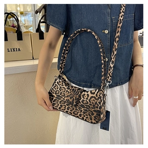 Close-up of leopard print baguette bag with adjustable strap on a female model