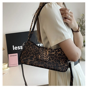 Leopard print baguette bag with flap closure shown on shoulder in lifestyle scene