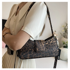 Detailed view of trendy leopard print baguette bag worn with a vintage beige dress
