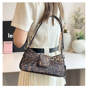Close-up of leopard print underarm bag texture and flap buckle on a woman's shoulder