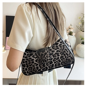 Close-up of leopard print underarm bag with glossy black strap and silver buckle detail