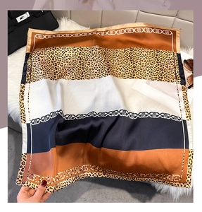 Detail of silk-feel scarf featuring leopard print, chain pattern and orange color blocks
