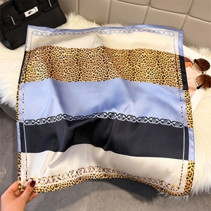 Detail of leopard print silk scarf flat lay with blue stripes and chain pattern