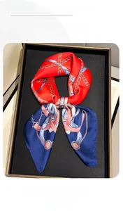Close-up of red and blue satin scarf with golden chain pattern in a black gift box